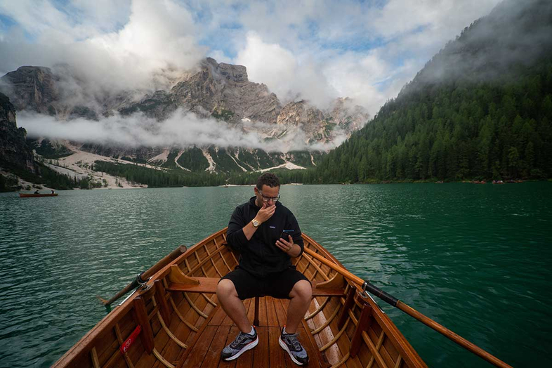 Tim Sykes in a boat in Italy checking the stocks on his top penny stocks list