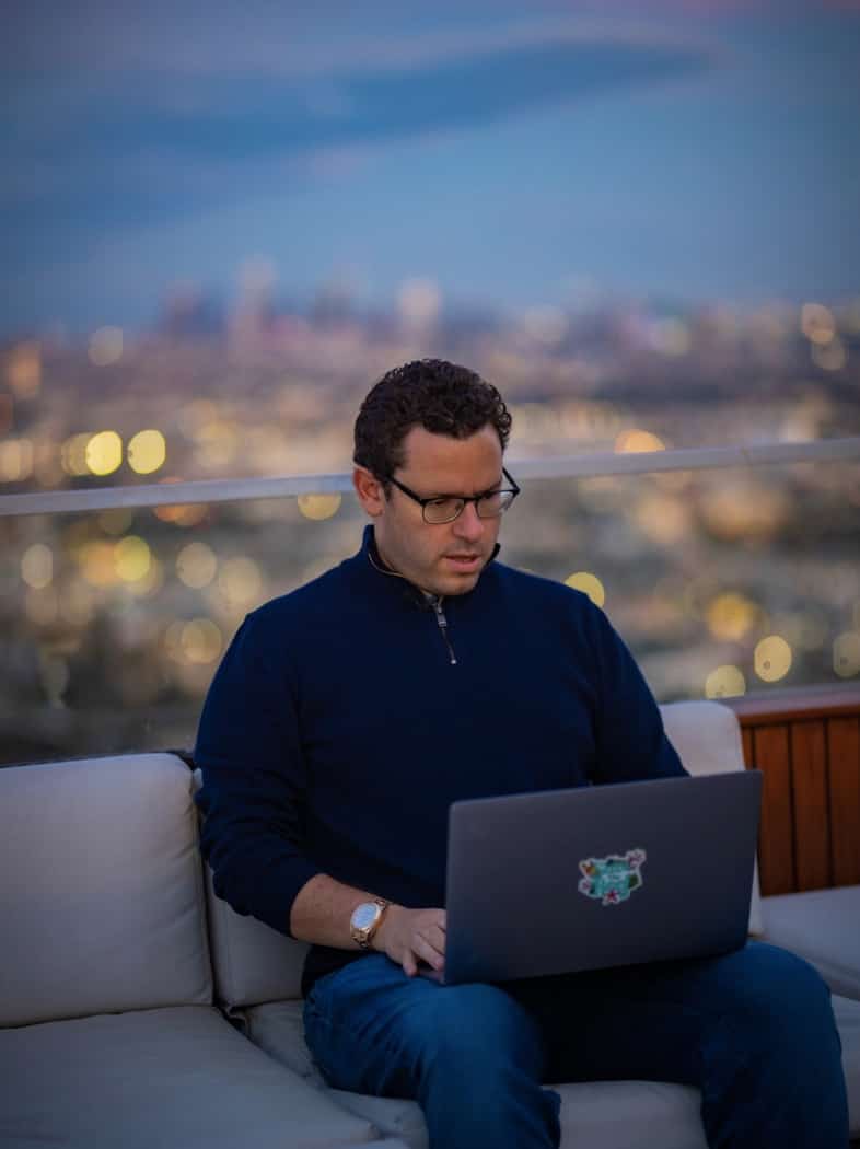 tim sitting looking at laptop with Southern California backdrop